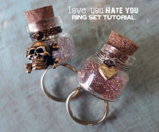 Love You Hate You Ring Set | DIY Valentines day Ideas

Materials: – 2 Fat Friar glass bottles
– 2 gold ring bases
– 12 inches of non-tarnish silver wire, 22 gauge
– 12 inches of non-tarnish gunmetal wire, 24 gauge
– 1 antique gold tiny heart charm
– 1 skull and crossbones charm
– 527 Glue
– Glitter
